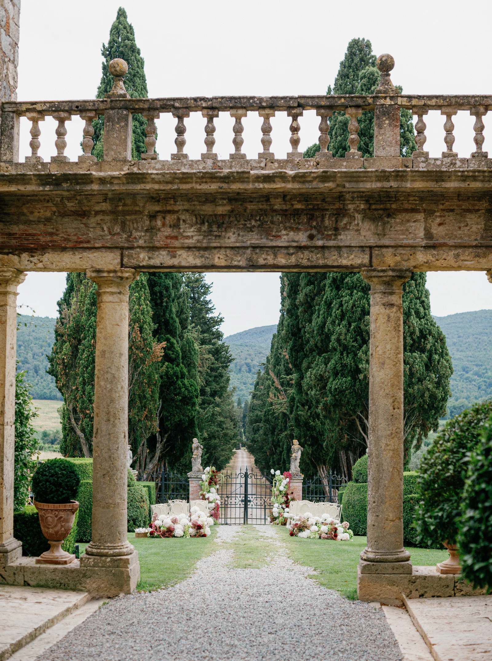 Stone gateway of Borgo Stomennano framing the cypress avenue and the Chianti hills, Tuscany