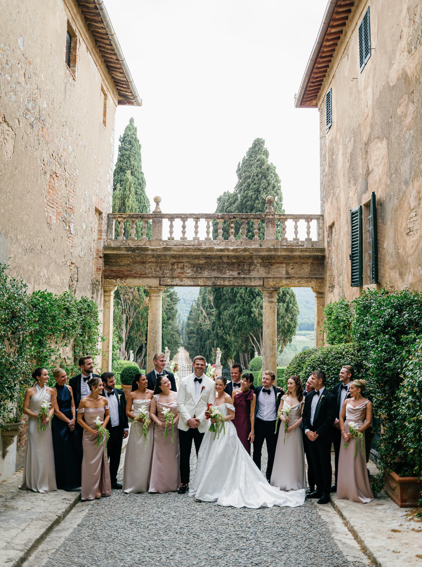 The wedding party gathered beneath the stone balustrade at the entrance of Borgo Stomennano, Chianti, Tuscany