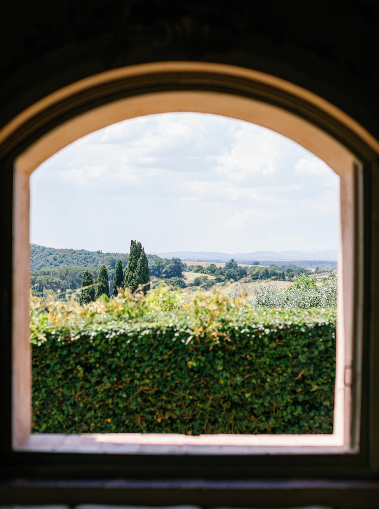 Arched window of Borgo Stomennano framing the Chianti hills, Tuscany