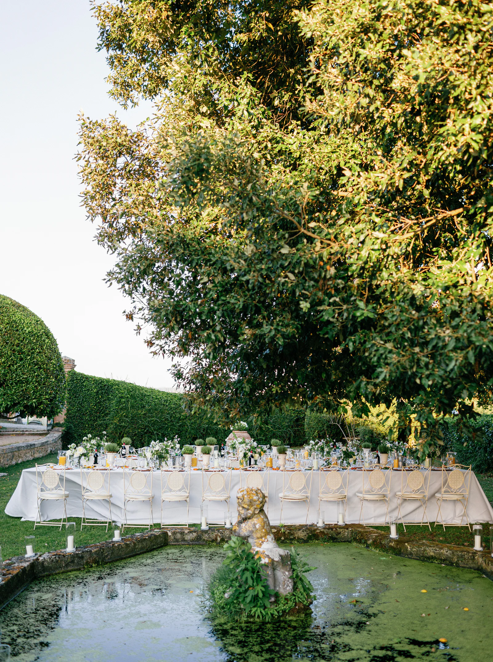Long tables beside the statue and water basin in the formal garden of Borgo Stomennano, Tuscany