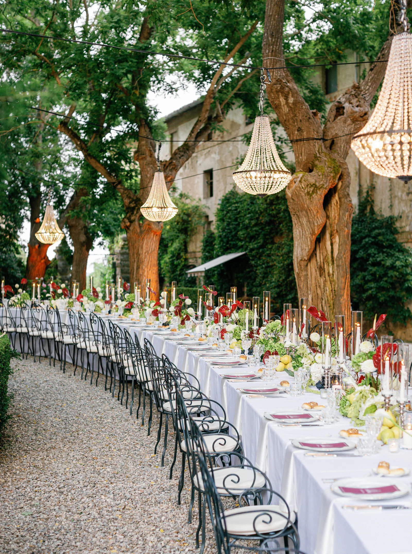 Curving table under crystal chandeliers in the garden of Borgo Stomennano at golden hour, Chianti
