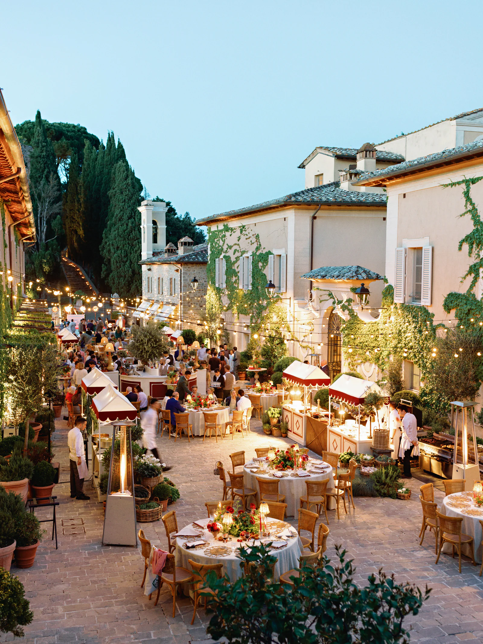 The borgo of Castiglion del Bosco, A Rosewood Hotel, at dusk, tables lit between the stone houses, Val d'Orcia