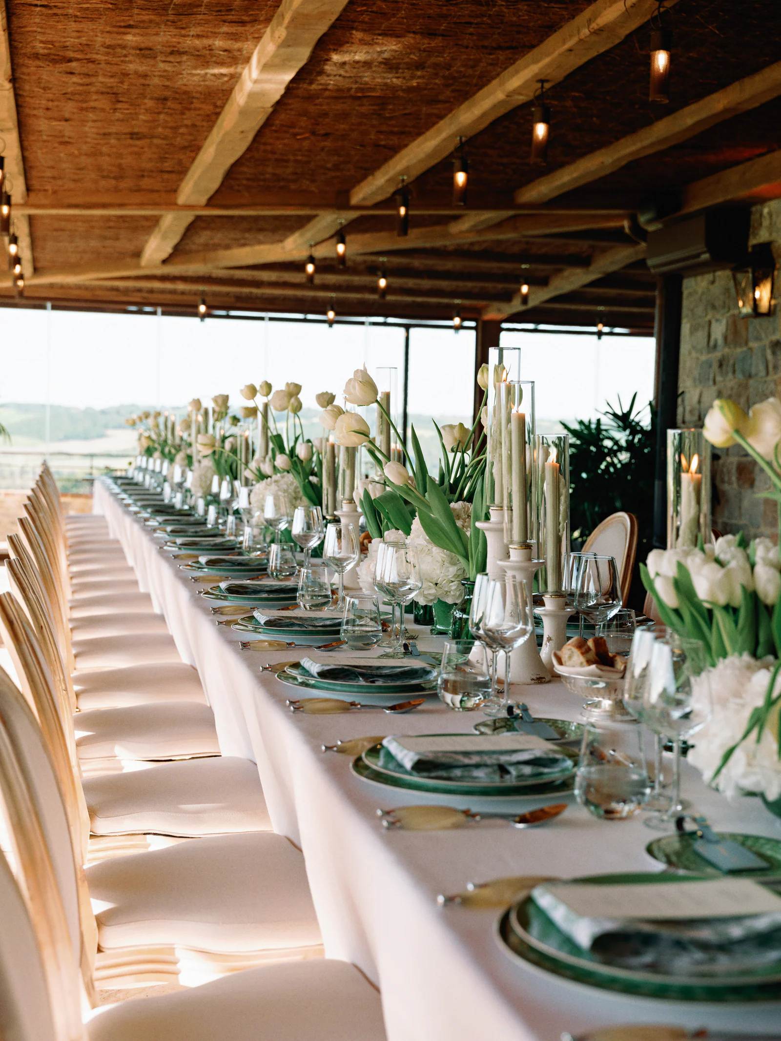 Long rehearsal-dinner table dressed with white tulips under the loggia at Castiglion del Bosco, A Rosewood Hotel, Tuscany