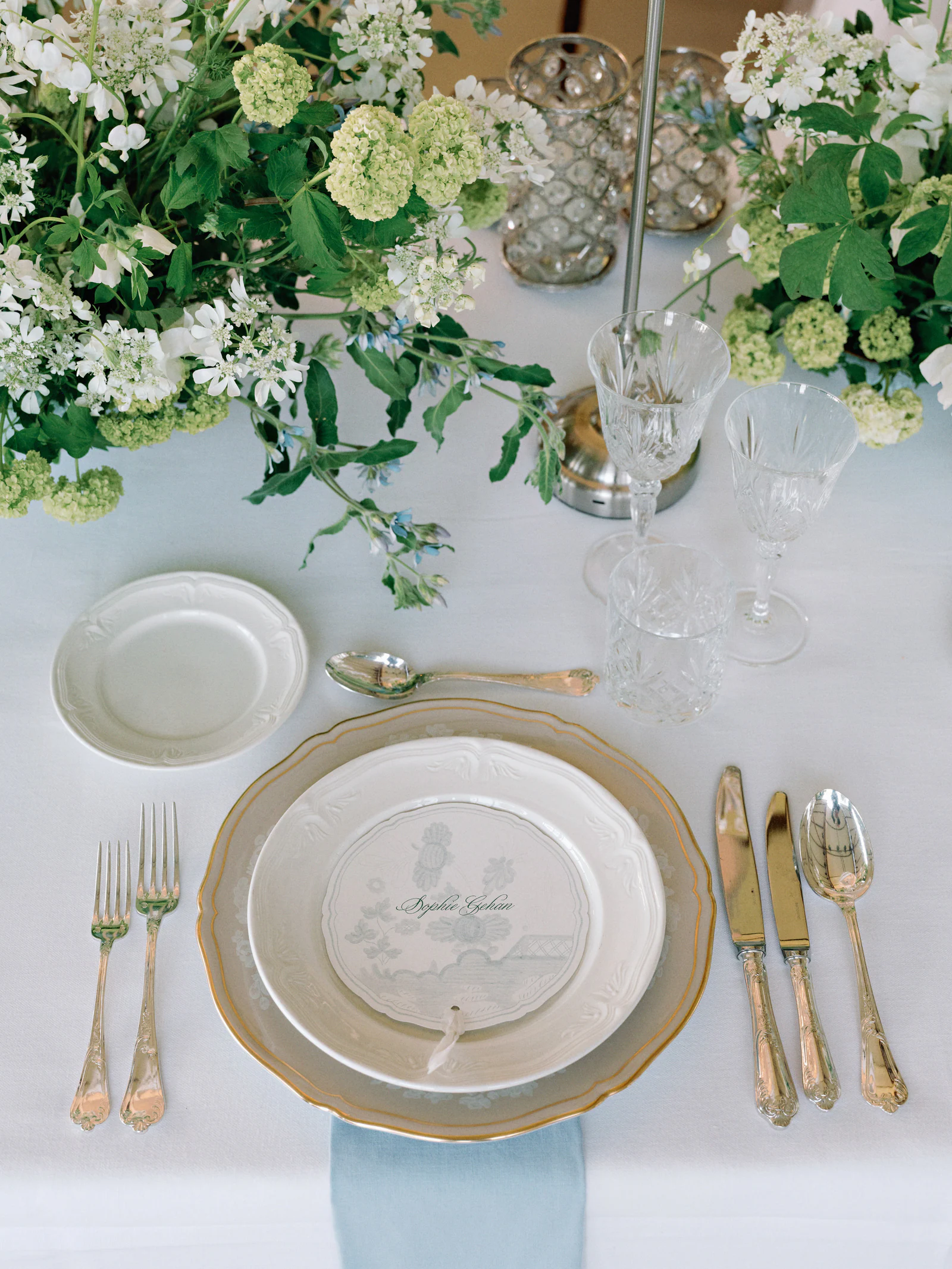Place setting with gold flatware and white florals at a Castiglion del Bosco, A Rosewood Hotel, wedding dinner, Tuscany