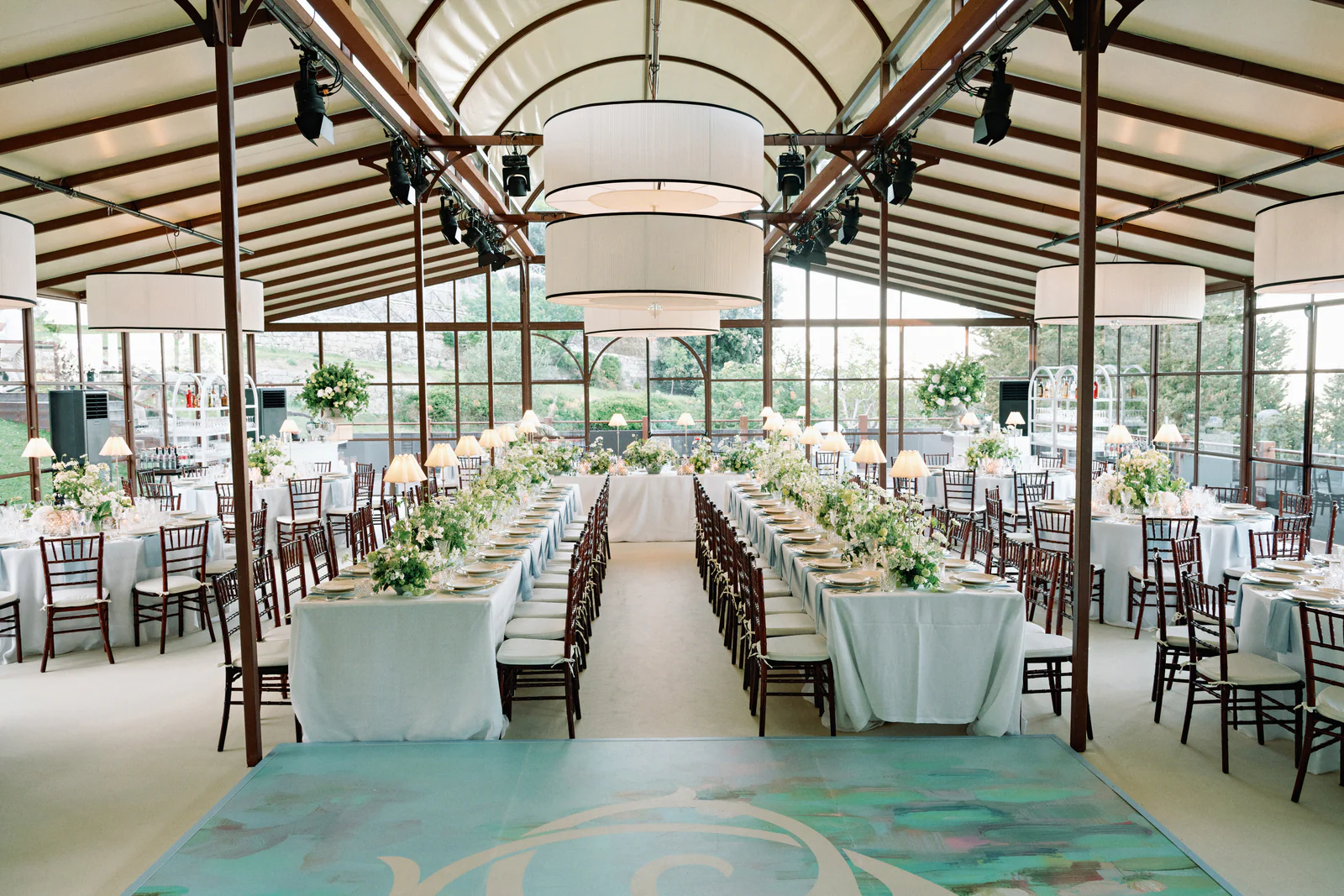 Glazed dinner pavilion at Castiglion del Bosco, A Rosewood Hotel, long ivory tables set for a Tuscany wedding