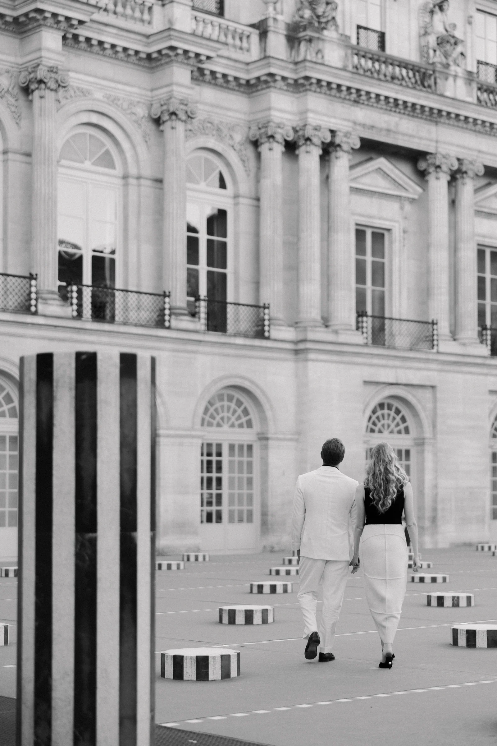The couple walking among the striped columns of the Palais-Royal, black and white, Paris