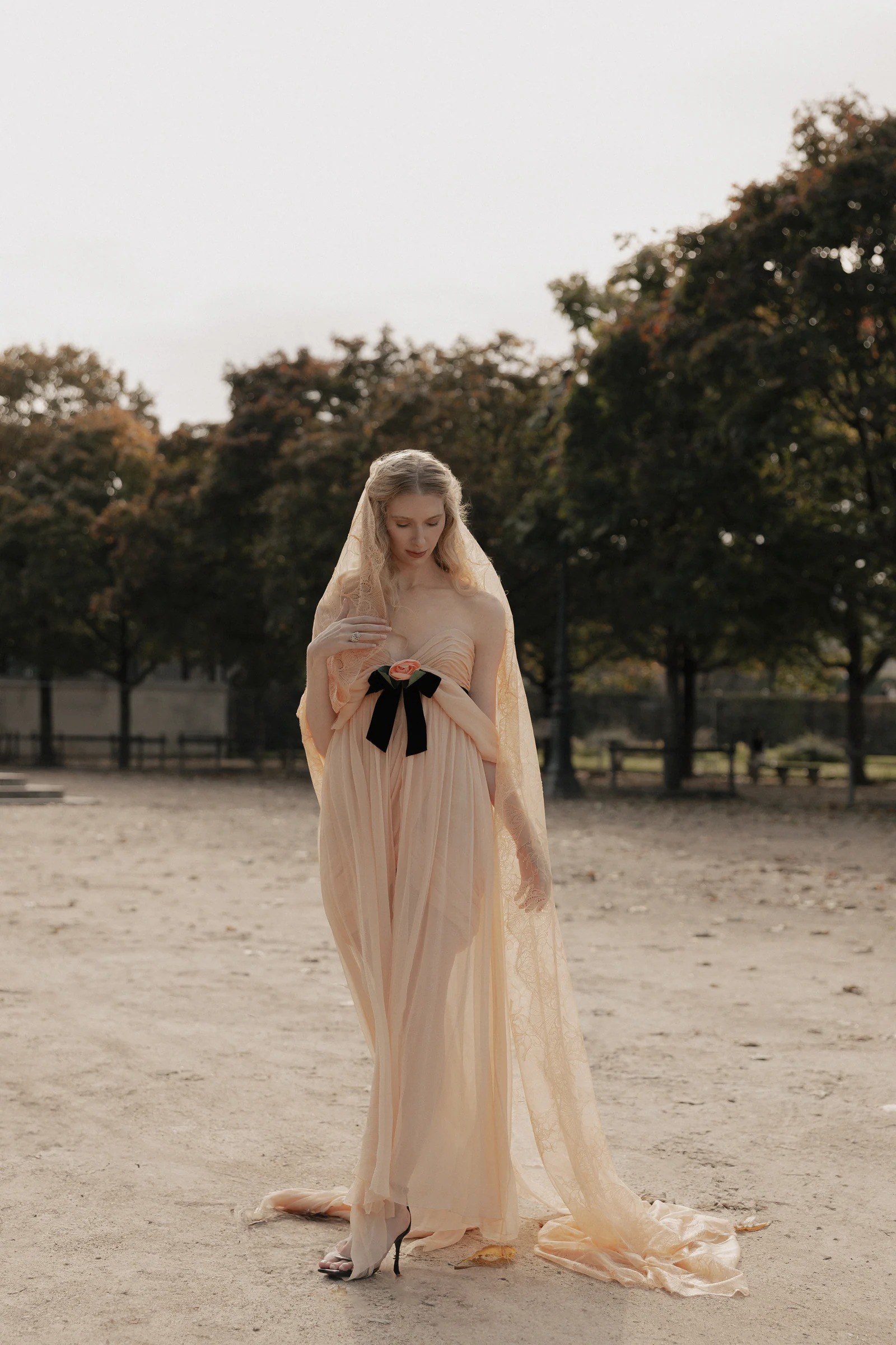 Bride in vintage Chanel and a long veil standing in the Tuileries garden, Paris