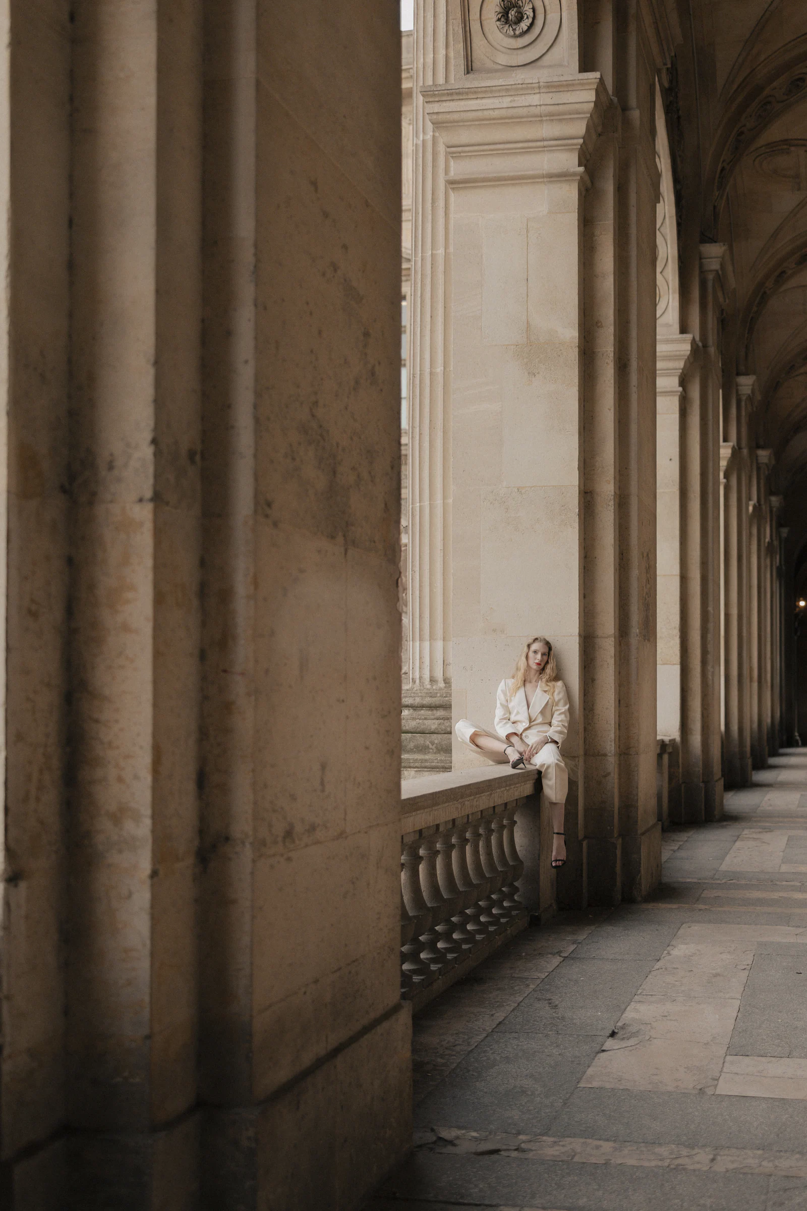 Bride under the colonnade of the Louvre in soft Paris daylight