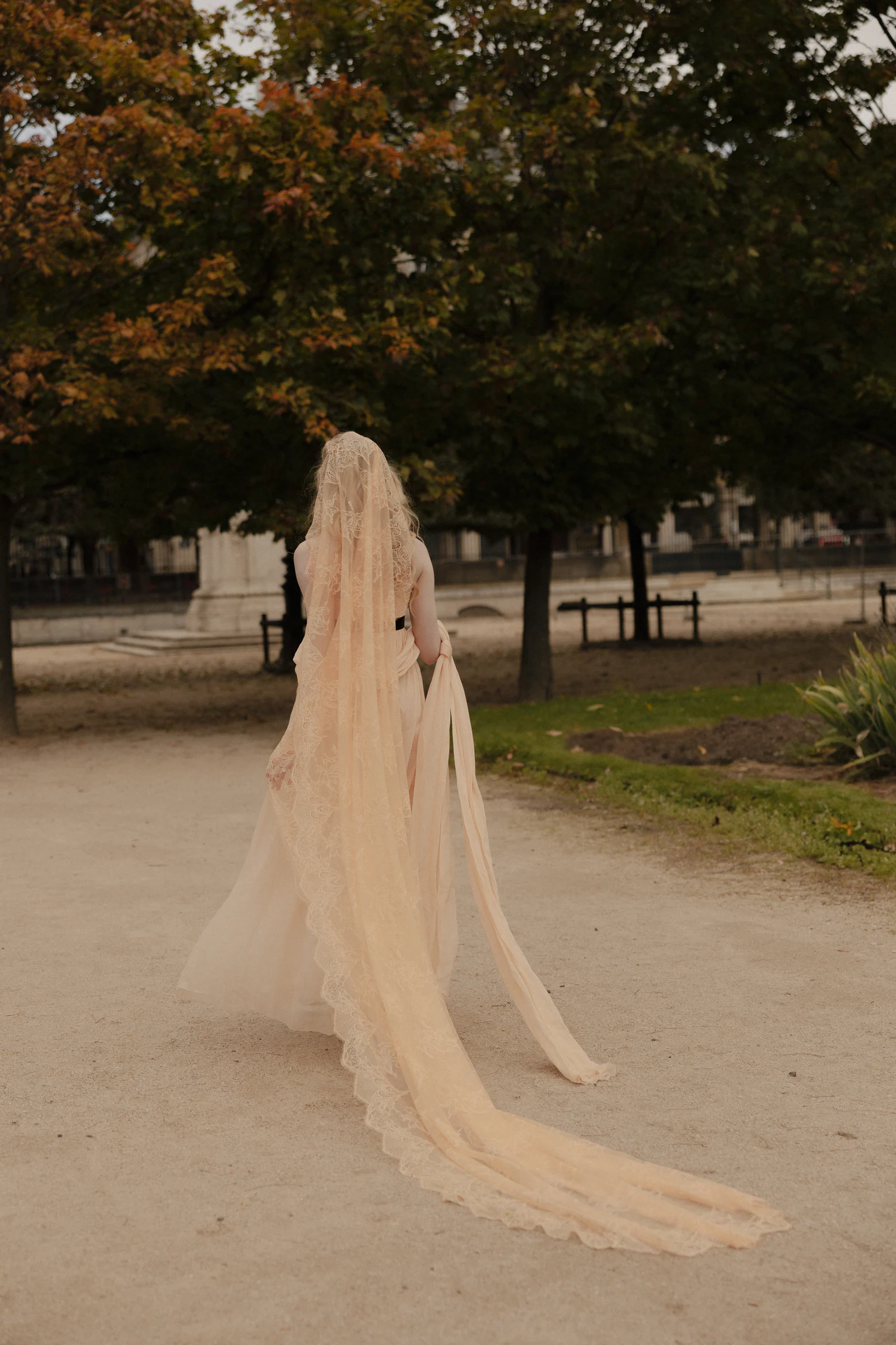 Bride's silk veil trailing along the Tuileries path in autumn light, Paris