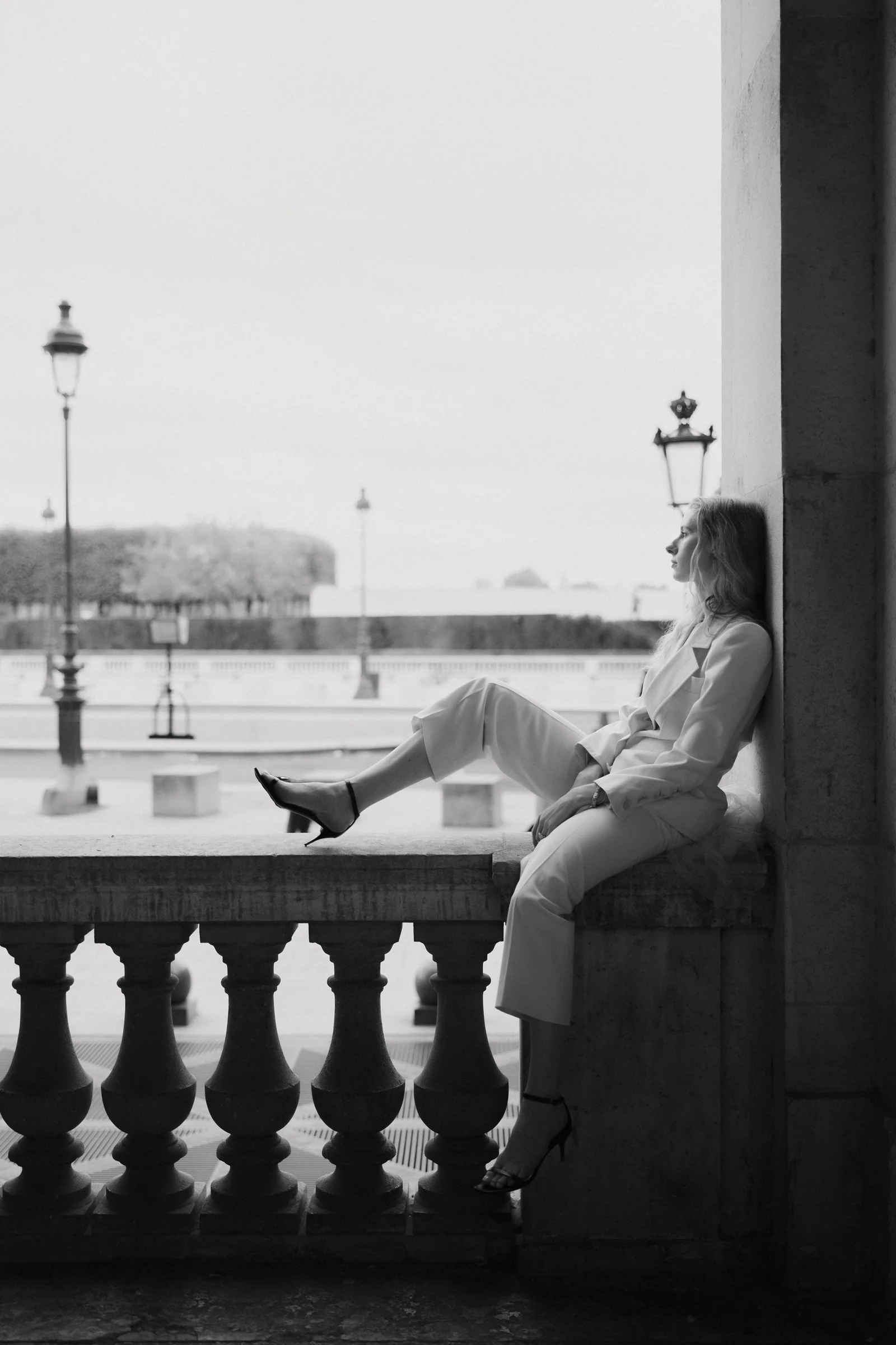Bride seated on the balustrade above the Seine under an arcade, black and white, Paris